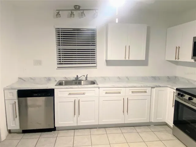 a kitchen with white cabinets appliances and a sink