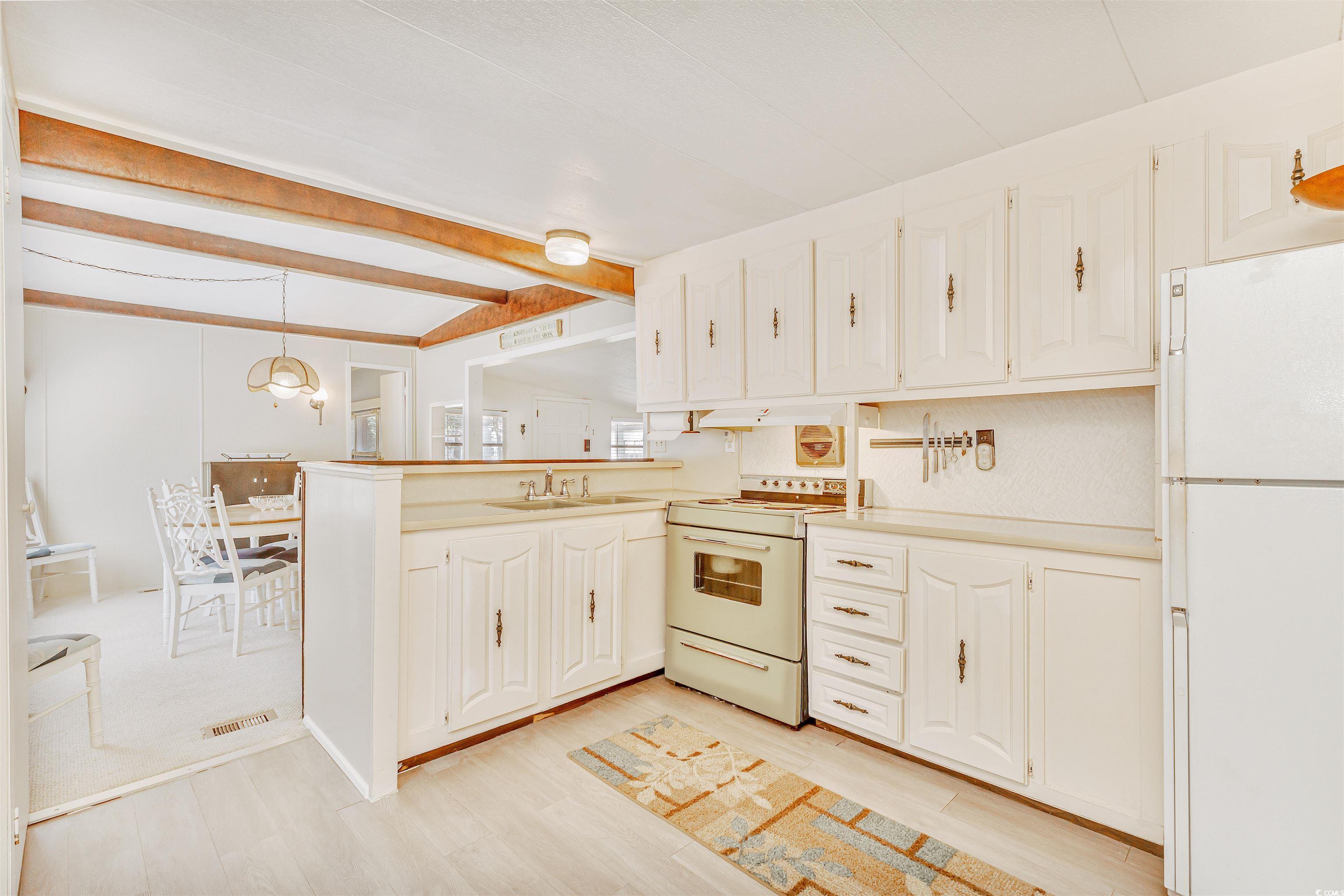 413 Delton Drive Murrells Inlet, SC 29576 - Photo 11 of 34 Kitchen featuring white appliances, kitchen peninsula, hanging light fixtures, and light hardwood / wood-style flooring
