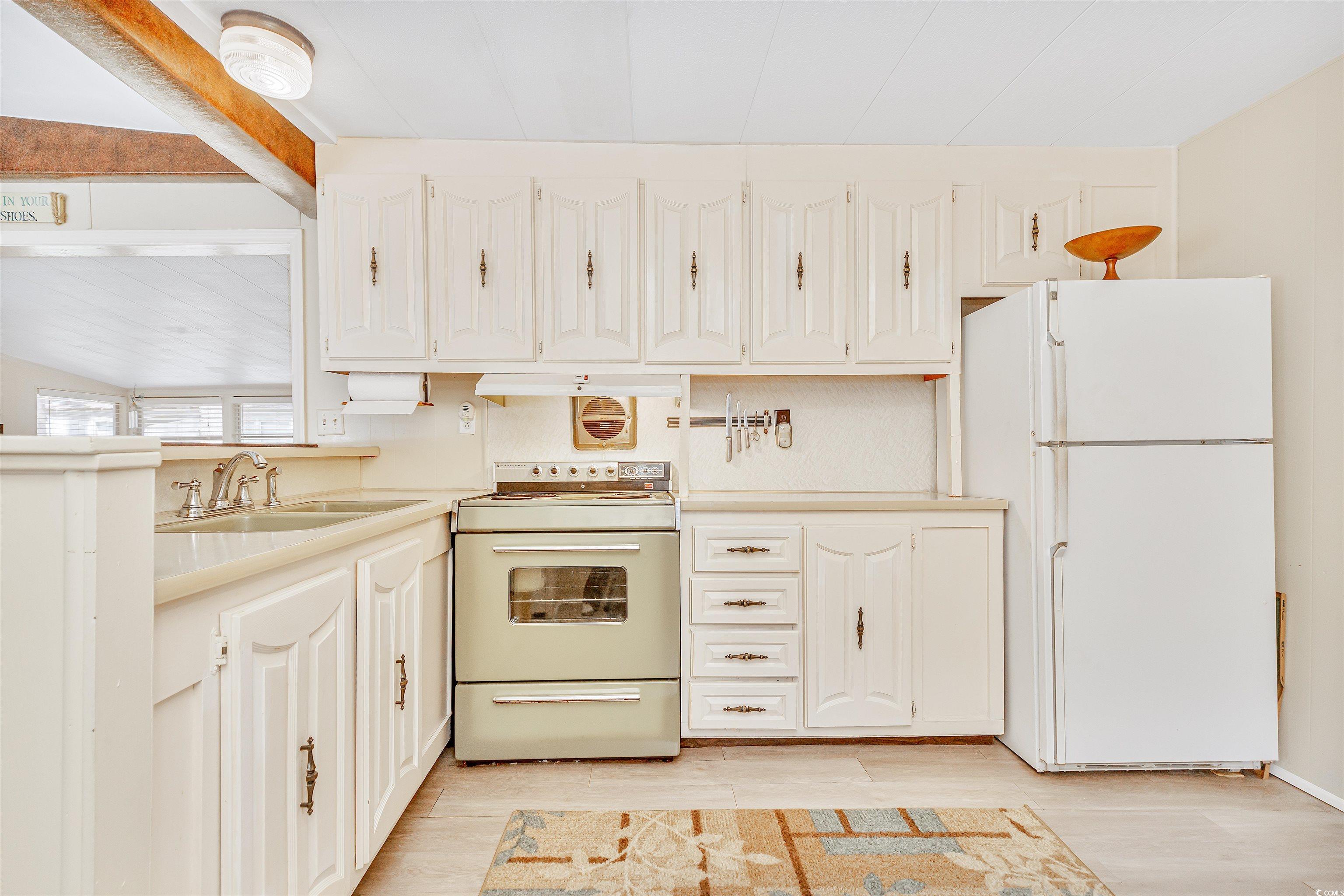 413 Delton Drive Murrells Inlet, SC 29576 - Photo 13 of 34 Kitchen with white appliances, a sink, light wood finished floors, and white cabinets