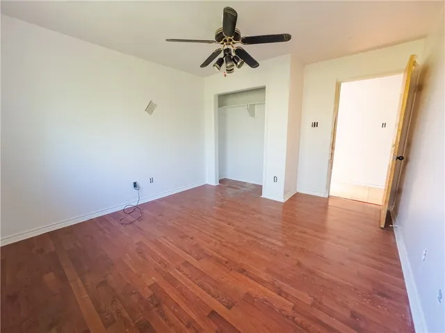a view of a room with wooden floor and a ceiling fan