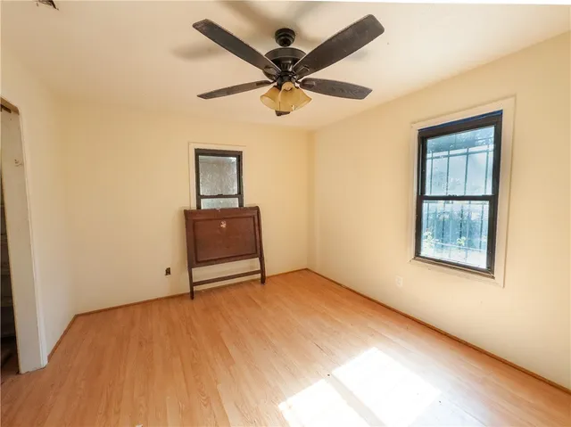 an empty room with wooden floor ceiling fan and windows