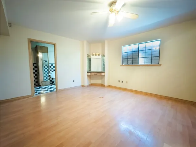 an empty room with chandelier fan and windows