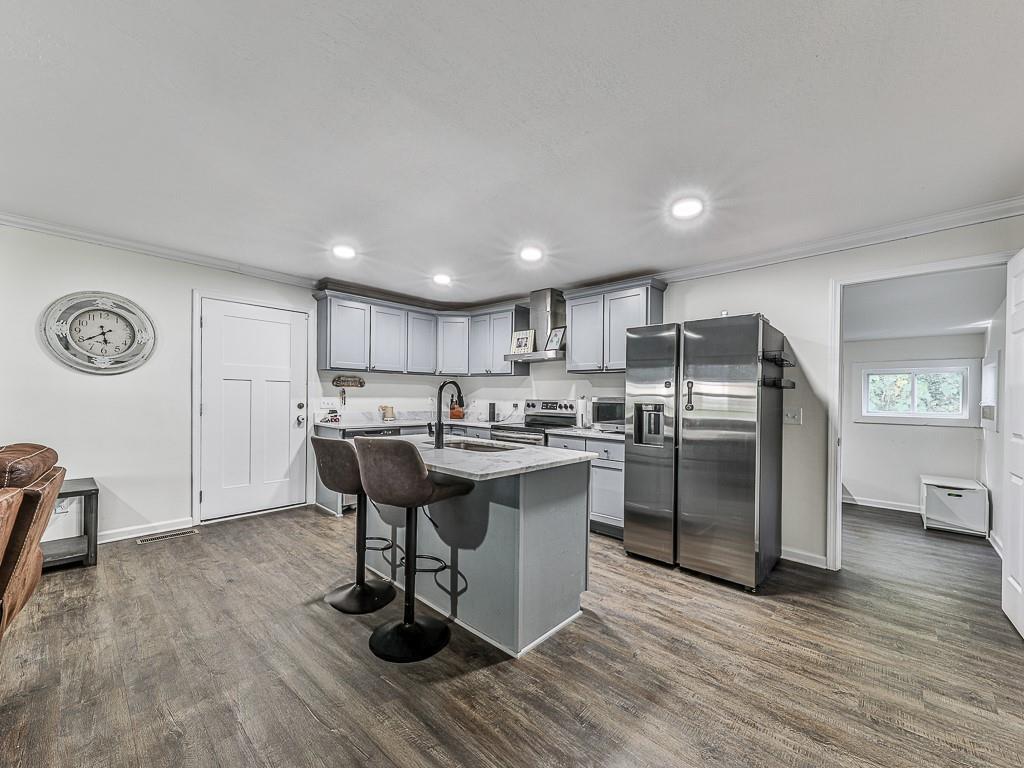 87 Jones Street Jasper, GA 30143 - Photo 4 of 25 a kitchen with stainless steel appliances a refrigerator a sink dishwasher a dining table and chairs with wooden floor