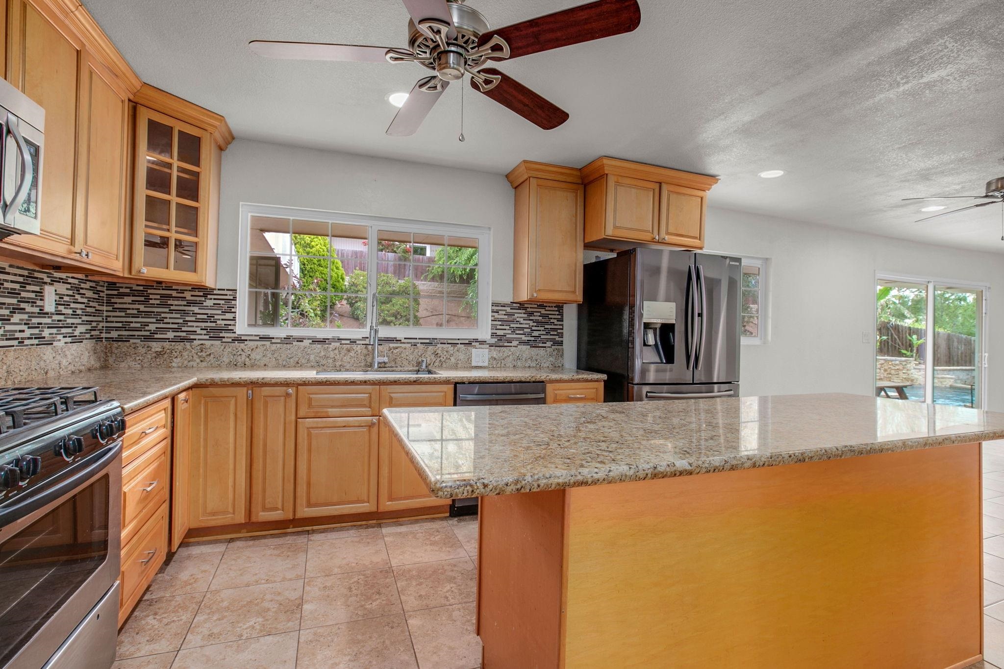 209 Casper Lane Vista, CA 92084 - Photo 8 of 12 a kitchen with stainless steel appliances granite countertop a sink a stove and a refrigerator