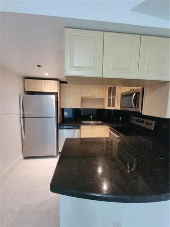 a kitchen with stainless steel appliances a refrigerator a stove a microwave and white cabinets