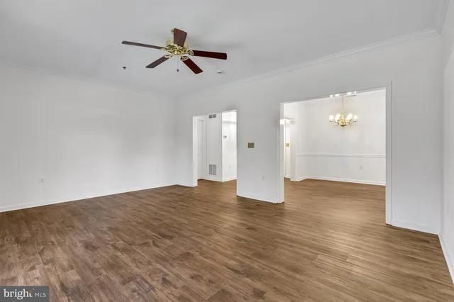 a view of empty room with wooden floor and ceiling fan