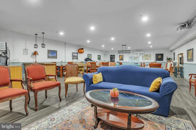 a living room with furniture kitchen view and a wooden floor
