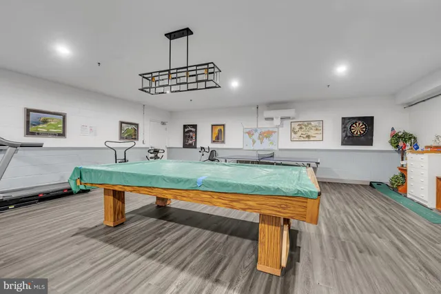 a living room with furniture pool table and a wooden floor