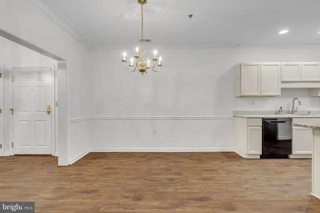 a view of empty room with wooden floor and kitchen view