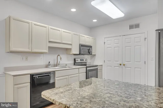 a kitchen with stainless steel appliances granite countertop a stove a sink and a refrigerator