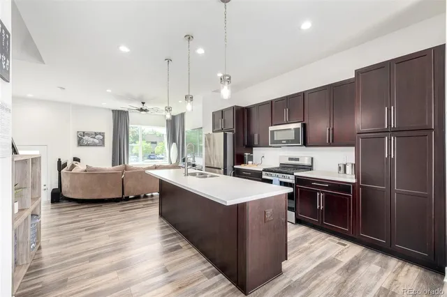a kitchen with kitchen island granite countertop a sink refrigerator and wooden floor
