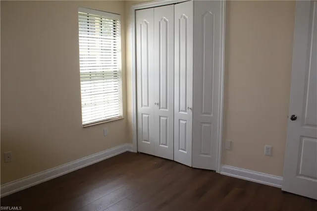 an empty room with wooden floor and windows with curtains