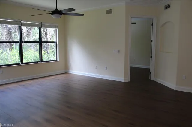 an empty room with wooden floor chandelier and windows