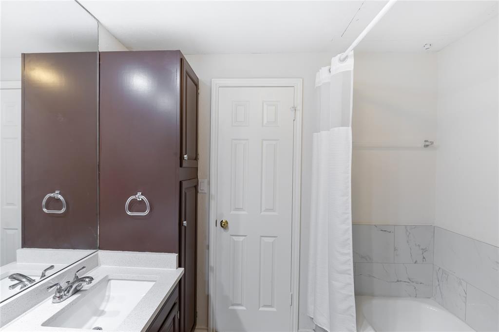 12680 Hillcrest Road, Unit 4101 Dallas, TX 75230 - Photo 19 of 37 Bathroom featuring a built-in vanity with a white countertop and integrated sink, dark wood-finish cabinetry, and a full-width wall mirror