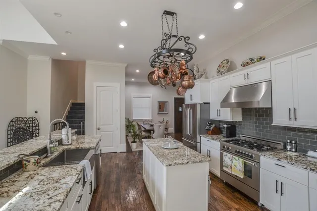 a kitchen with stainless steel appliances granite countertop a sink dishwasher stove refrigerator and couches with wooden floor