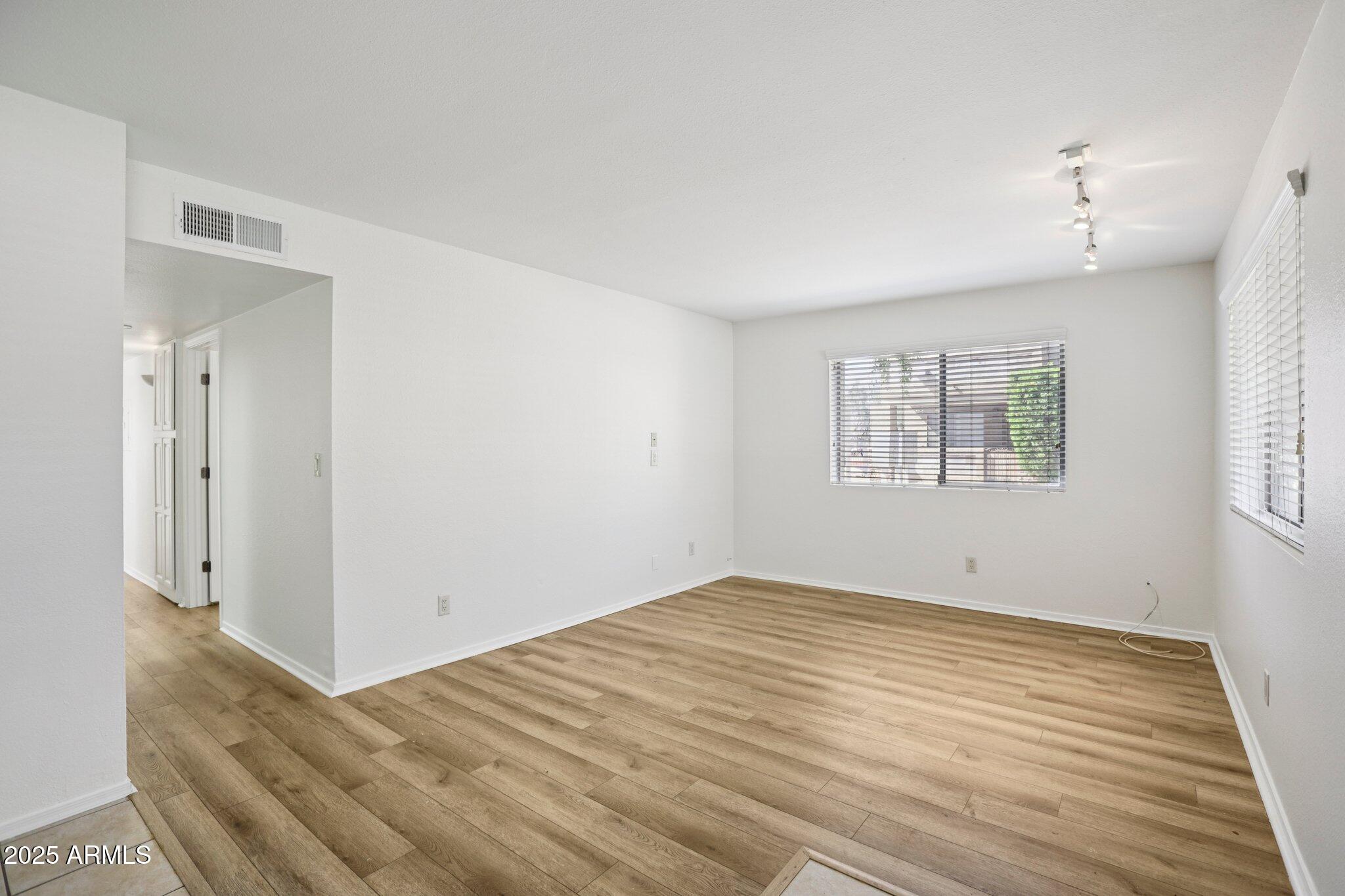 303 North Miller Road, Unit 1001 Scottsdale, AZ 85257 - Photo 4 of 20 a view of an empty room with wooden floor and a window