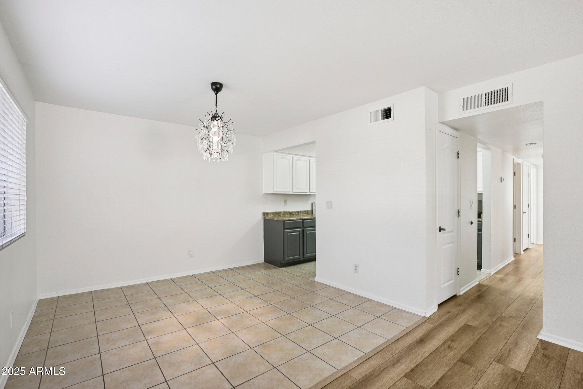 303 North Miller Road, Unit 1001 Scottsdale, AZ 85257 - Photo 7 of 20 a view of an empty room with wooden floor and kitchen view