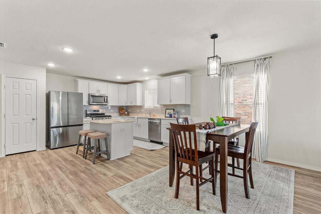 14056 Ilderton Street Pilot Point, TX 76258 - Photo 9 of 34 a kitchen with a table chairs refrigerator and microwave