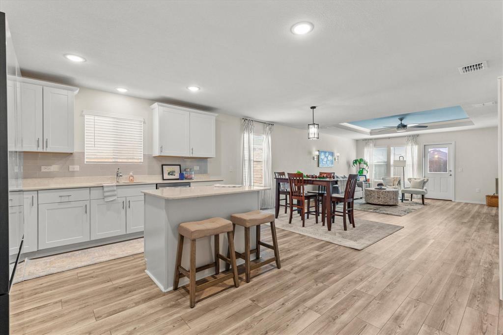 14056 Ilderton Street Pilot Point, TX 76258 - Photo 33 of 34 a kitchen with stainless steel appliances granite countertop dining table chairs stove and white cabinets