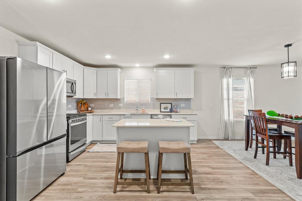 14056 Ilderton Street Pilot Point, TX 76258 - Photo 6 of 34 a kitchen with a refrigerator a dining table and chairs