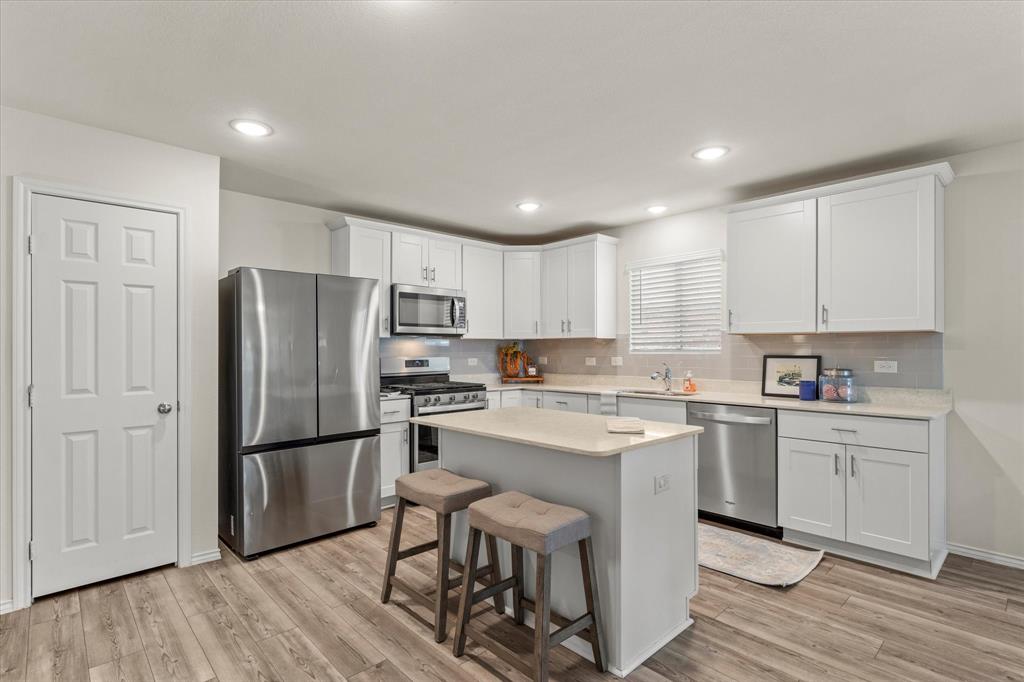 14056 Ilderton Street Pilot Point, TX 76258 - Photo 7 of 34 a kitchen with white cabinets and stainless steel appliances