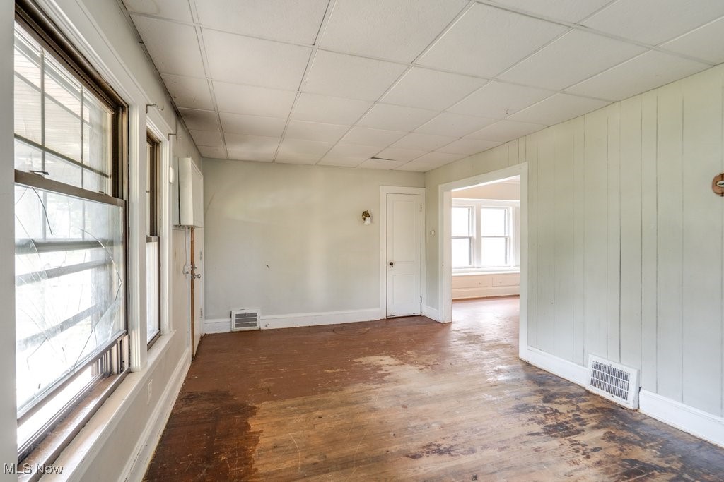 1618 Catalpa Road Cleveland, OH 44112 - Photo 11 of 33 Unfurnished room featuring hardwood / wood-style floors, a paneled ceiling, and wooden walls