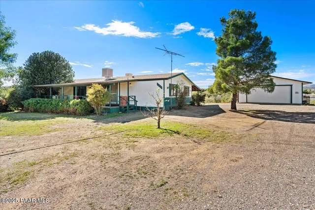 a backyard of a house with table and chairs under an umbrella