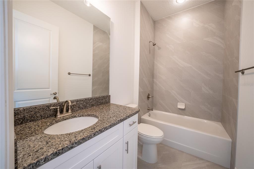 4727 Southeast 25th Loop Ocala, FL 34480 - Photo 18 of 29 a bathroom with a granite countertop sink a toilet and bathtub