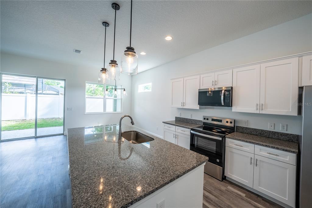 4727 Southeast 25th Loop Ocala, FL 34480 - Photo 4 of 29 a kitchen with stainless steel appliances granite countertop a sink a stove and a wooden floor