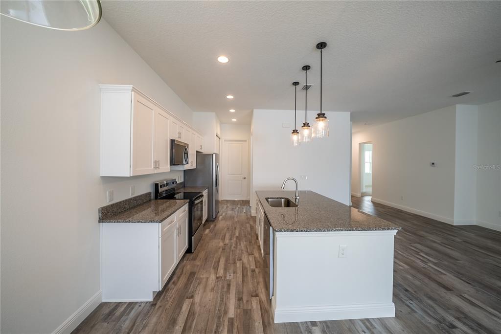 4727 Southeast 25th Loop Ocala, FL 34480 - Photo 7 of 29 a kitchen with kitchen island granite countertop a sink a counter top space and stainless steel appliances