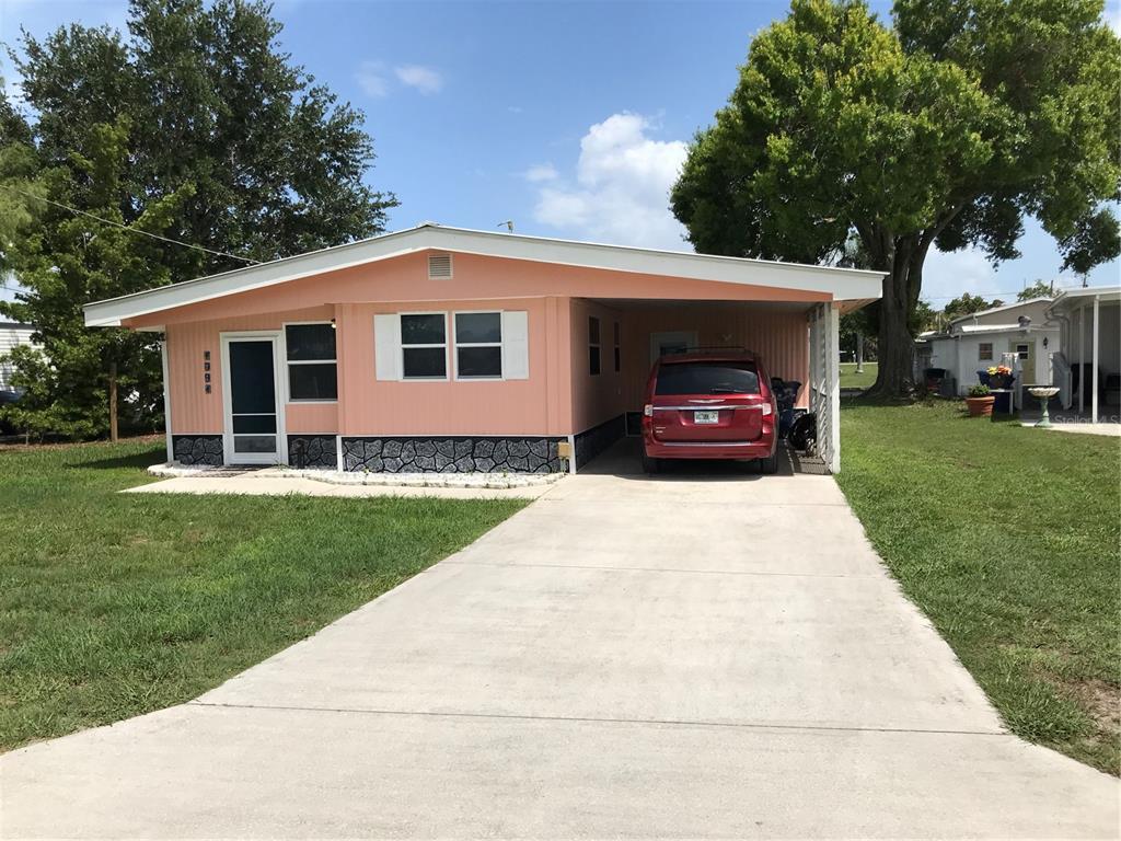 1091 Lemon Street Okeechobee, FL 34974 - Photo 2 of 19 a car parked in front of a house with a garden
