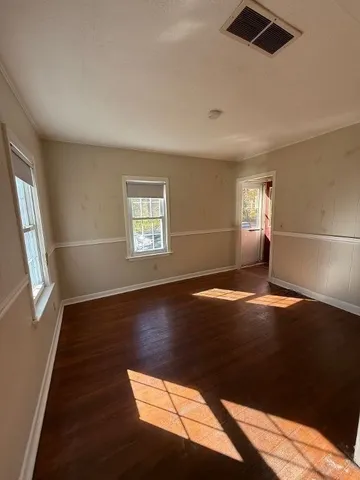 a view of an empty room with wooden floor and a window
