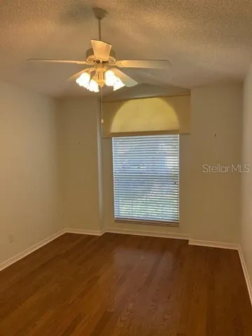 a view of empty room with wooden floor and fan