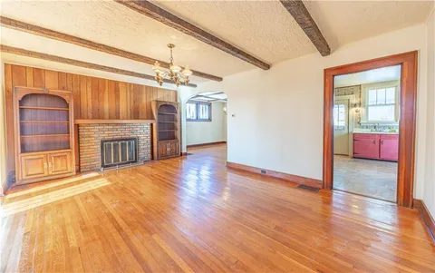 a view of a livingroom with wooden floor and a kitchen