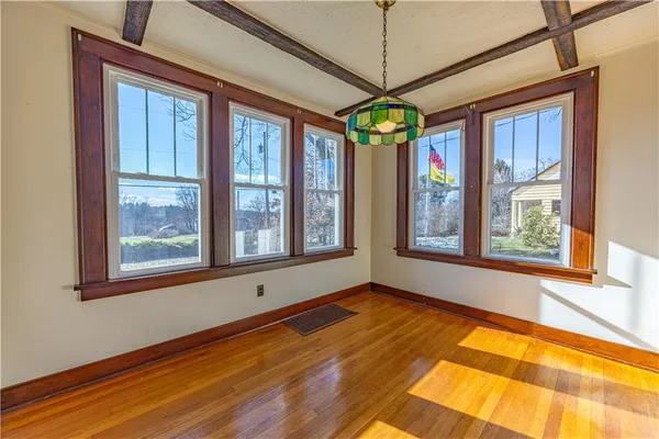 a view of an empty room with a window and wooden floor