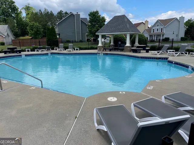 a view of swimming pool with outdoor seating and house in the background