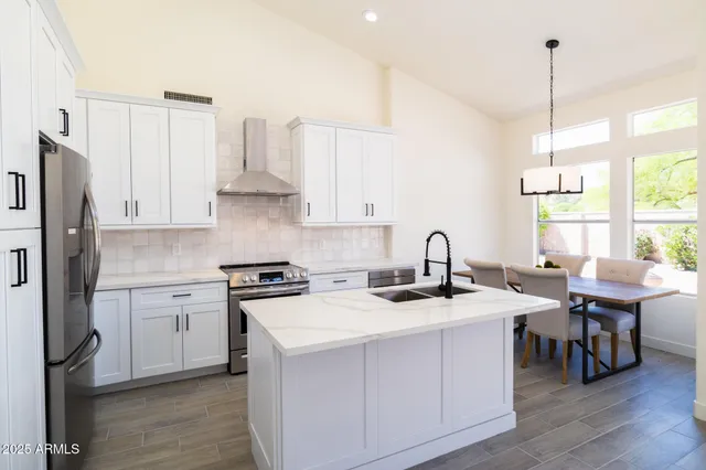 a kitchen with stainless steel appliances granite countertop a stove a sink dishwasher and a refrigerator with wooden floor