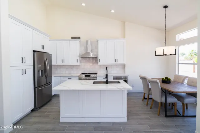 a kitchen with stainless steel appliances kitchen island a table chairs refrigerator and microwave