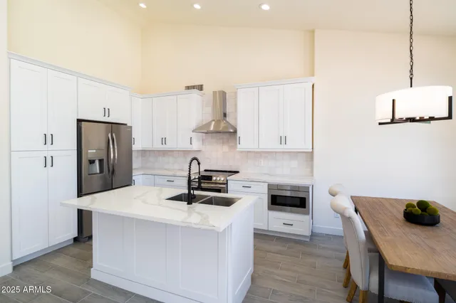 a kitchen with stainless steel appliances a stove a refrigerator a sink a stove and white cabinets