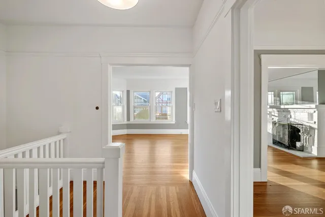 a view of a hallway with wooden floor and a living room