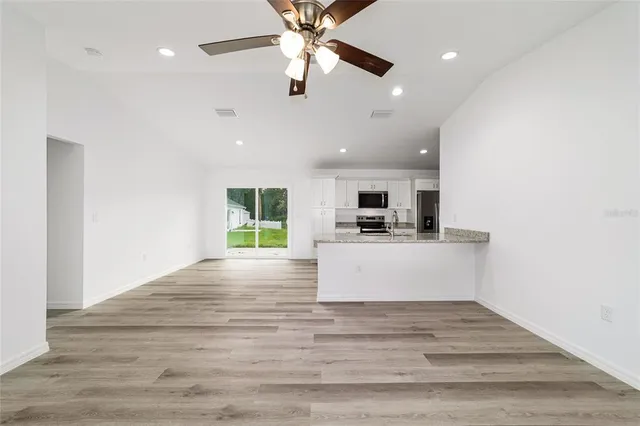 a view of living room with kitchen island stainless steel appliances refrigerator stove and a window