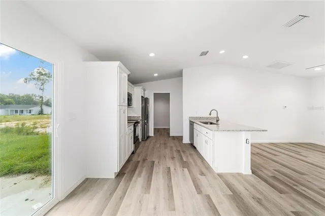 a view of a kitchen with fridge and wooden floor