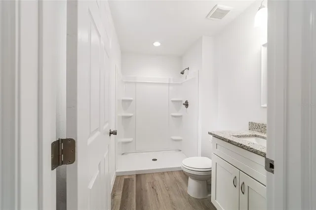 a bathroom with a granite countertop sink a toilet and shower