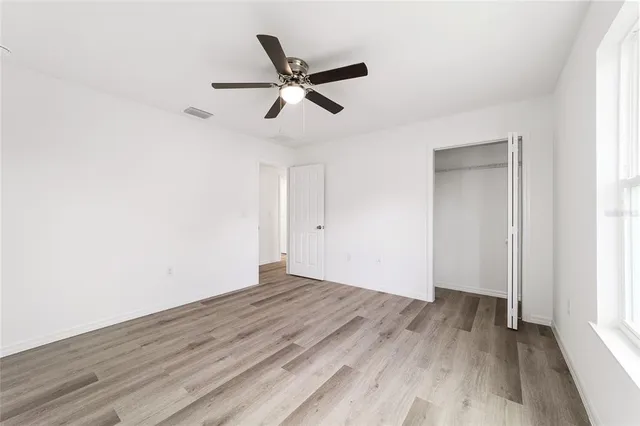 a view of empty room with wooden floor and fan