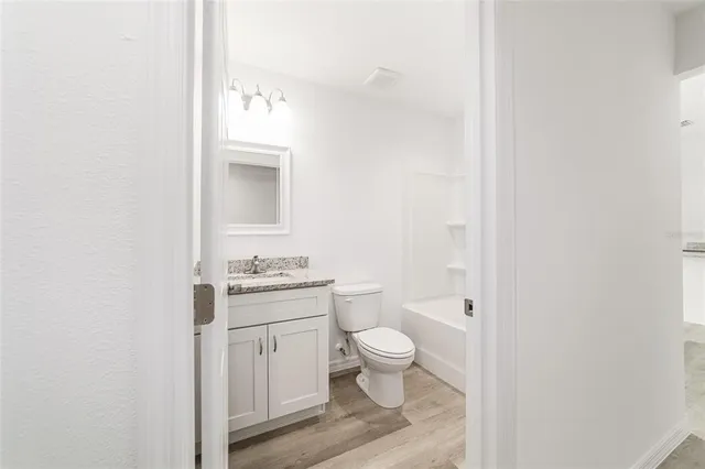 a bathroom with a granite countertop toilet a sink and a mirror