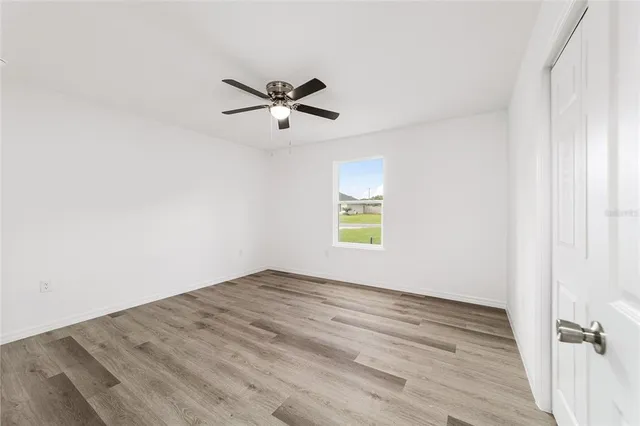 a view of empty room with wooden floor and fan