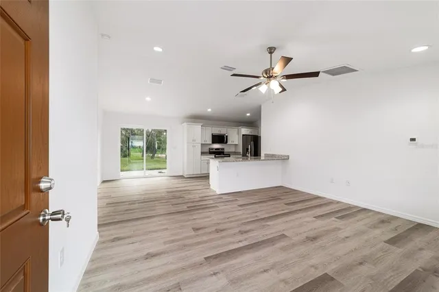 a view of empty room with wooden floor and a ceiling fan