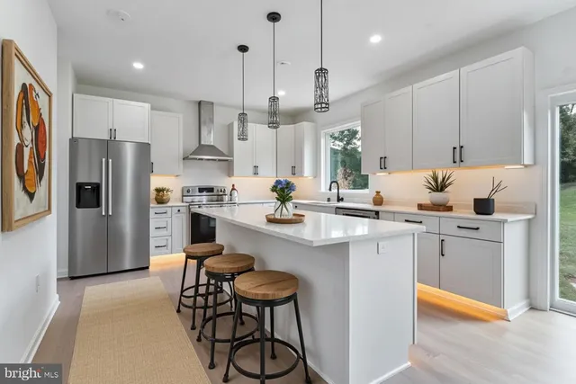 a large kitchen with stainless steel appliances kitchen island granite countertop a lot of counter space and wooden floors