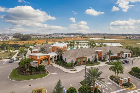 a view of swimming pool that has lawn chairs with plants and trees