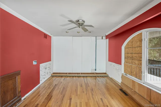 a view of empty room with wooden floor and fan